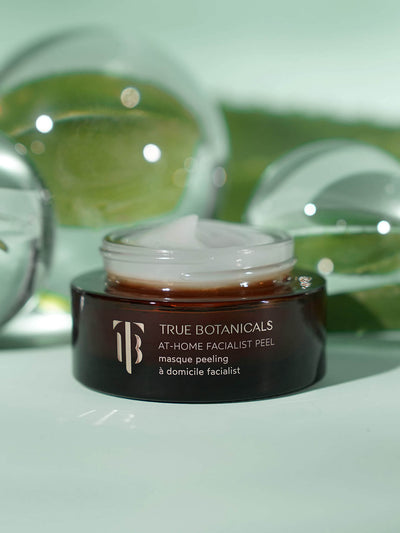 True Botanicals At-Home Facialist Peel
A luxurious exfoliating mask in an amber glass jar, displayed with a smooth, creamy texture. The background features soft green tones and reflective glass elements, evoking a sense of nature and renewal.