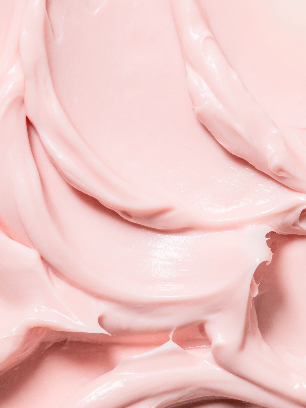 Close-up texture shot of True Botanicals Chebula Extreme Cream showing a thick, luxurious blush-pink cream with a glossy, whipped consistency and soft swirled folds.