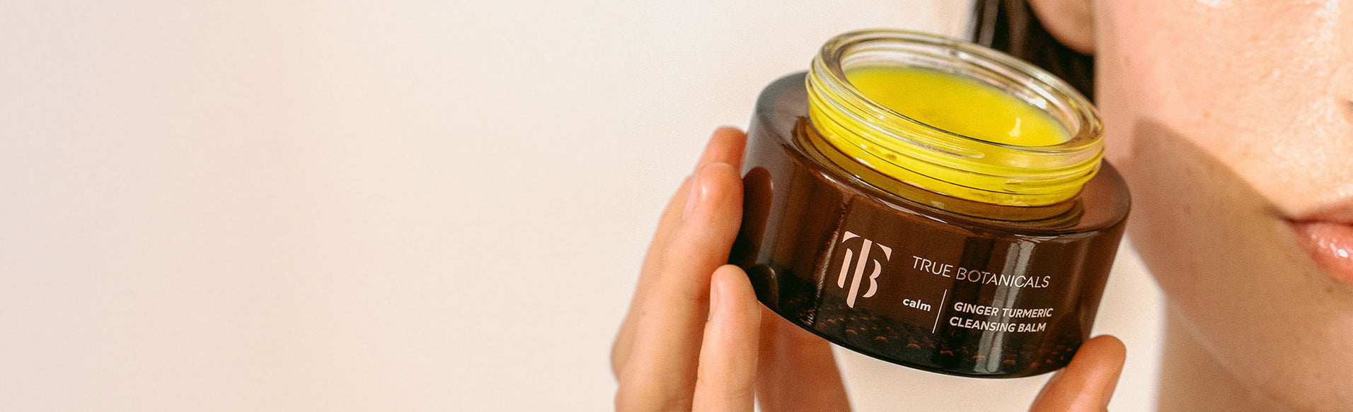 Model holding Ginger Turmeric Cleansing Balm up close.