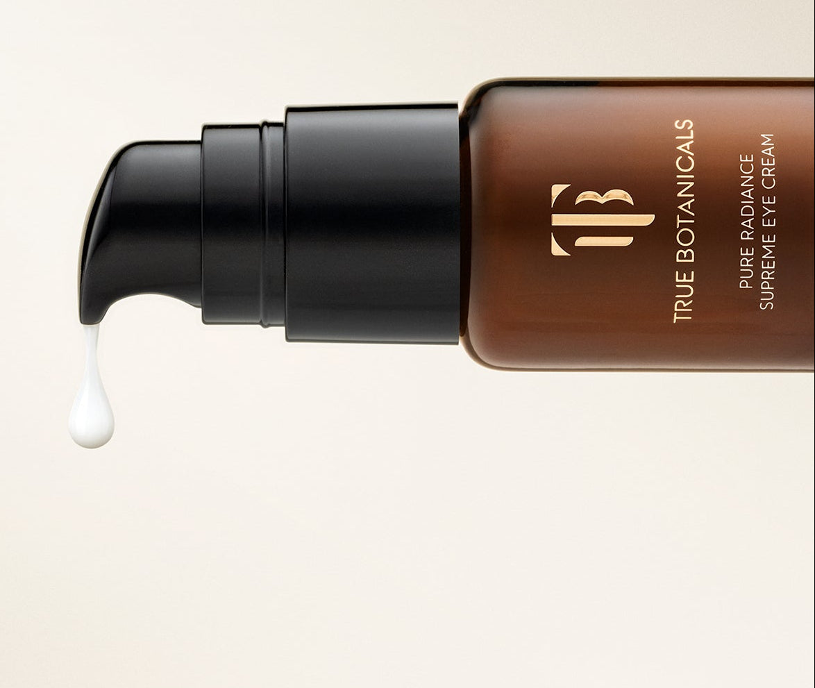 True Botanicals eye cream with a droplet of cream on a beige background