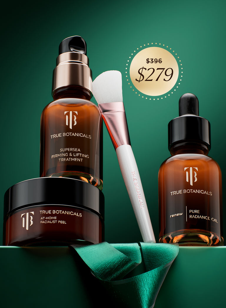 This image highlights True Botanicals skincare products, including the At-Home Facialist Peel, SuperSEA Firming & Lifting Treatment, and Pure Radiance Oil. Accompanied by a sleek application brush and a green ribbon accent, the setup exudes a luxurious and professional spa-like feel, ideal for achieving radiant, healthy skin at home.