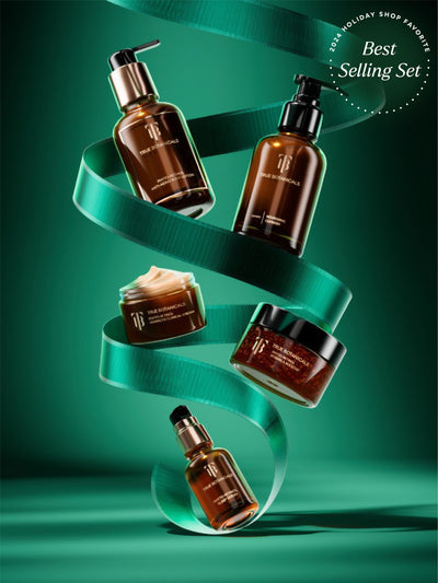 Promotional image showcasing the 2024 Holiday Shop Favorite Best Selling Set by True Botanicals. The set features Phyto-Retinol Vitamin A Booster, Nourishing Cleanser, Phyto-Retinol Advanced Clinical Cream, Resurfacing Body Mask, and Phyto-Retinol Vitamin A Serum, elegantly arranged in a vertical spiral with a green ribbon and a dark green background.