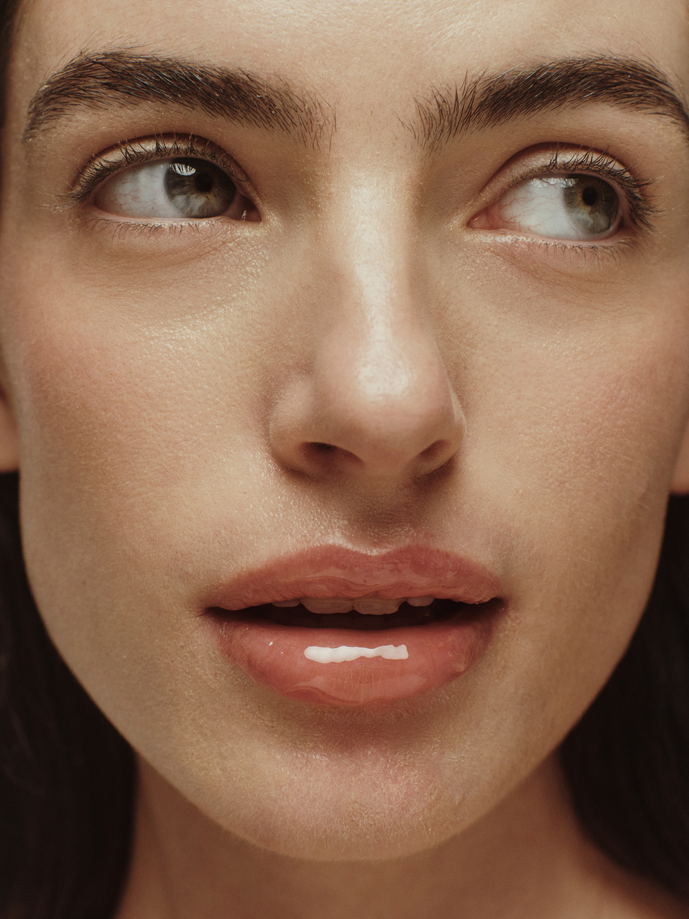 Model with glossy lips wearing True Botanicals Lipid Lip Hydrating Lip Oil.
