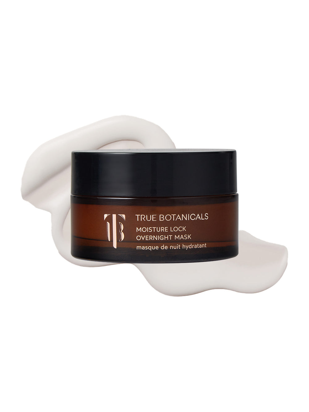 A jar of True Botanicals Moisture Lock Overnight Mask in a dark amber container with a black lid is displayed against a white background. Behind the jar, a smooth swirl of creamy, white mask is spread, highlighting its rich, hydrating texture. The label emphasizes its overnight moisturizing benefits.