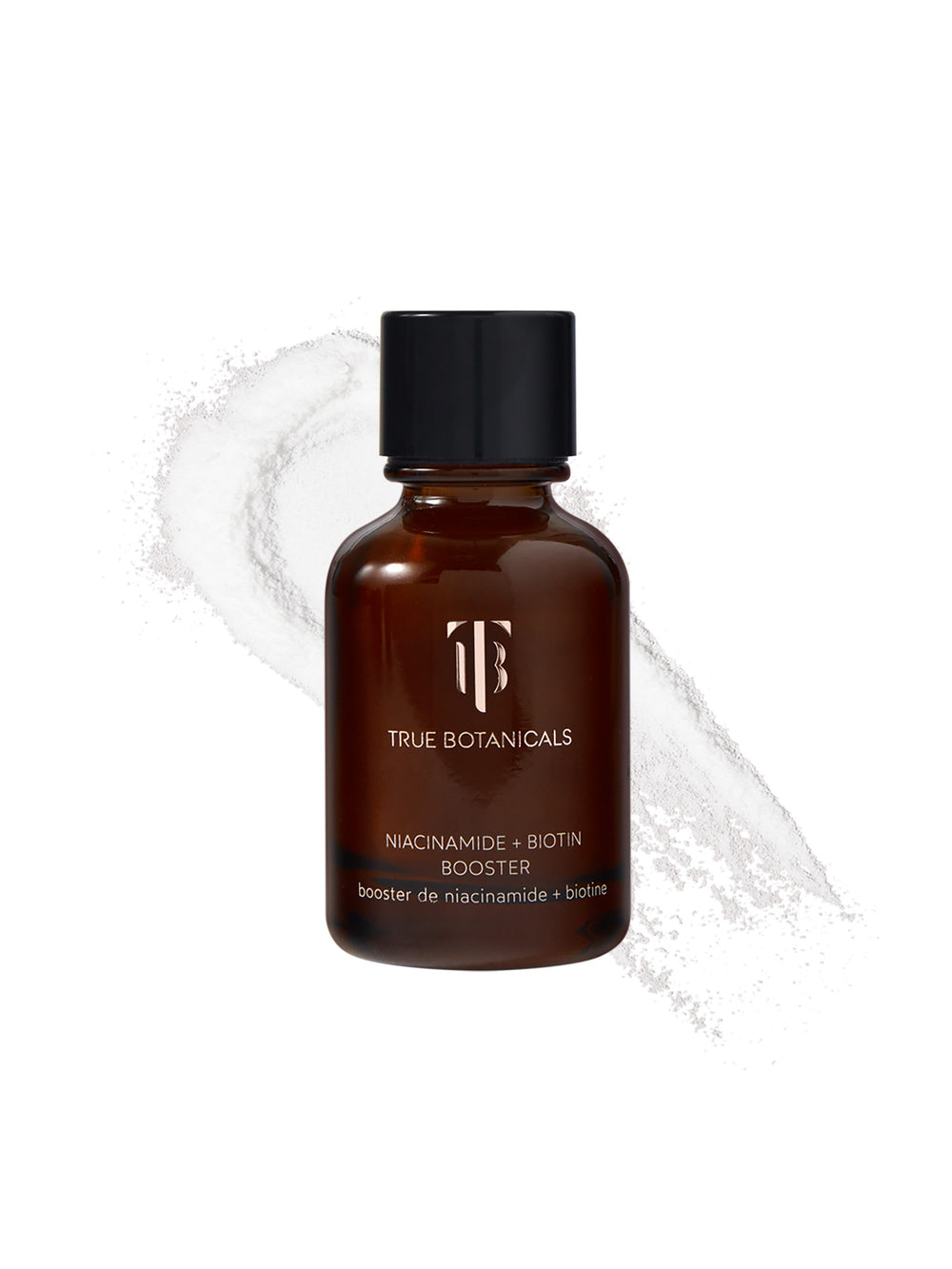 A bottle of True Botanicals Niacinamide + Biotin Booster in a dark amber glass container with a black screw cap is displayed against a white background. Behind the bottle, a swirl of fine, white powder is spread, emphasizing its concentrated, powdered formula. The label highlights its key ingredients, niacinamide and biotin.