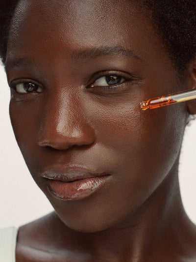 Woman applying Clear Pure Radiance Oil with a dropper, a face oil for oily and breakout-prone skin