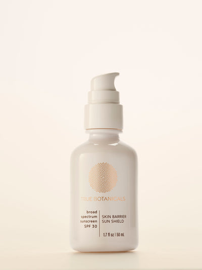 A white pump bottle of TRUE BOTANICALS Broad Spectrum Sunscreen SPF 30, centered against a warm off-white background.